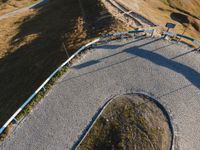 the skateboarder in yellow is riding a long trail of concrete path through a field