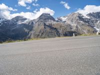 the young child is walking down the street in front of the mountain range with a skateboard