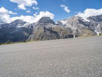 the young child is walking down the street in front of the mountain range with a skateboard