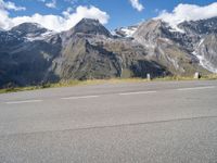 the young child is walking down the street in front of the mountain range with a skateboard