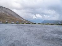 a motorcycle parked in a deserted parking lot on a mountain side with a few clouds