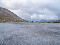 a motorcycle parked in a deserted parking lot on a mountain side with a few clouds