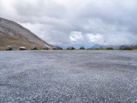 a motorcycle parked in a deserted parking lot on a mountain side with a few clouds