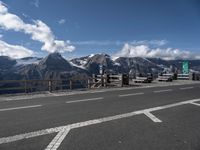 a view of the mountains, including snow capped peaks and a paved highway with benches