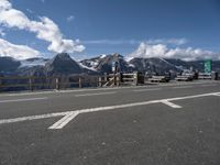 a view of the mountains, including snow capped peaks and a paved highway with benches