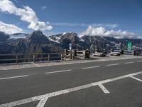 a view of the mountains, including snow capped peaks and a paved highway with benches