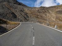 a road running through a mountainous mountain on a sunny day by the side of the hill