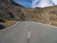 a road running through a mountainous mountain on a sunny day by the side of the hill