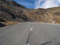 a road running through a mountainous mountain on a sunny day by the side of the hill