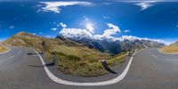 fish - eye lens of a road in the mountains next to two hills and some clouds