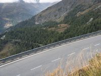 a man riding a bicycle on the road next to a forest in the mountains in a hilly area