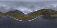 two winding roads with mountains in the background and a sign pointing up at each other