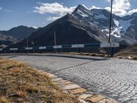 a car is parked on a cobble stone path in the mountains with mountains behind