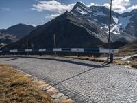 a car is parked on a cobble stone path in the mountains with mountains behind