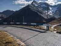 a car is parked on a cobble stone path in the mountains with mountains behind