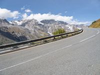 a road with mountains and sky in the background, including a motorcycle on one side