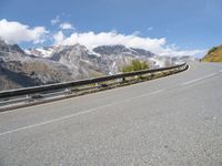 a road with mountains and sky in the background, including a motorcycle on one side