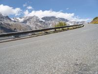 a road with mountains and sky in the background, including a motorcycle on one side