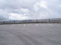 an empty parking lot in a mountain with mountains behind it and clouds on the top of the mountain