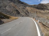 a long empty road with no traffic sign and hills in the background, all on either side of it