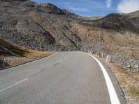 a long empty road with no traffic sign and hills in the background, all on either side of it