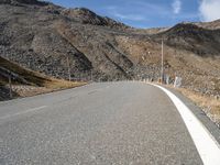 a long empty road with no traffic sign and hills in the background, all on either side of it