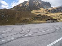 a motorcycle is parked on the empty asphalted road, in front of the mountain