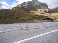 a motorcycle is parked on the empty asphalted road, in front of the mountain