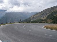 there is a small motorcycle that is on the road near mountains and clouds as well