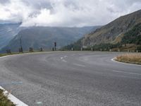 there is a small motorcycle that is on the road near mountains and clouds as well