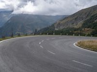 there is a small motorcycle that is on the road near mountains and clouds as well