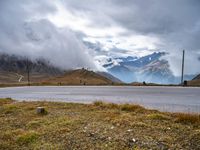 the mountains around an empty highway are covered with clouds and snowflakes on a foggy day