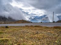 a car parked on the side of the road near a mountain slope under a partly cloudy sky