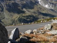 a person is riding their motorcycle down the side of a mountain road in front of a large boulder