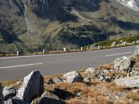 a person is riding their motorcycle down the side of a mountain road in front of a large boulder