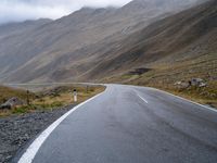 an empty road in the middle of a beautiful, mountainous area with some mountain range on either side of it