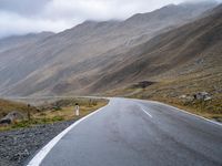 an empty road in the middle of a beautiful, mountainous area with some mountain range on either side of it