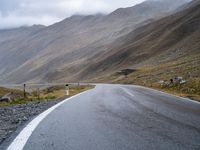 an empty road in the middle of a beautiful, mountainous area with some mountain range on either side of it