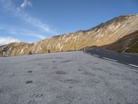 the curved road goes along the side of the mountain range of mountains with snow and clouds above