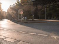 a street with a crosswalk at an intersection in front of a bridge at sunset