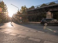 a street with a crosswalk at an intersection in front of a bridge at sunset