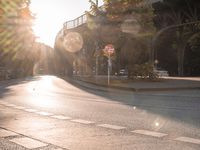 a street with a crosswalk at an intersection in front of a bridge at sunset