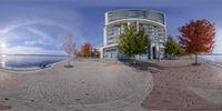 a fish eye lens photo of a tall building with red trees in front of it