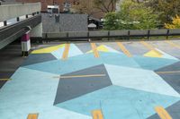 a parking garage has an unusual painted mural on it's surface, outside of a building