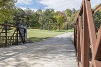 a wooden bridge over a paved path in the autumntime with fall foliage and a path winding through it