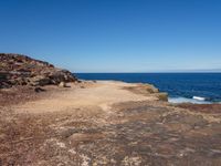 rocks, water and blue sky surround the beach near rocks and small sand - covered shoreline