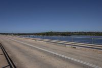 a man in a red truck drives on the road along with another car nearby and a body of water in the distance