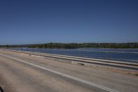 a man in a red truck drives on the road along with another car nearby and a body of water in the distance