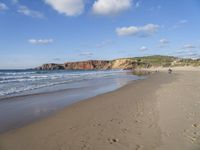 people are on the beach with the tide coming in and footprints in the sand leading to the ocean