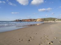 people are on the beach with the tide coming in and footprints in the sand leading to the ocean